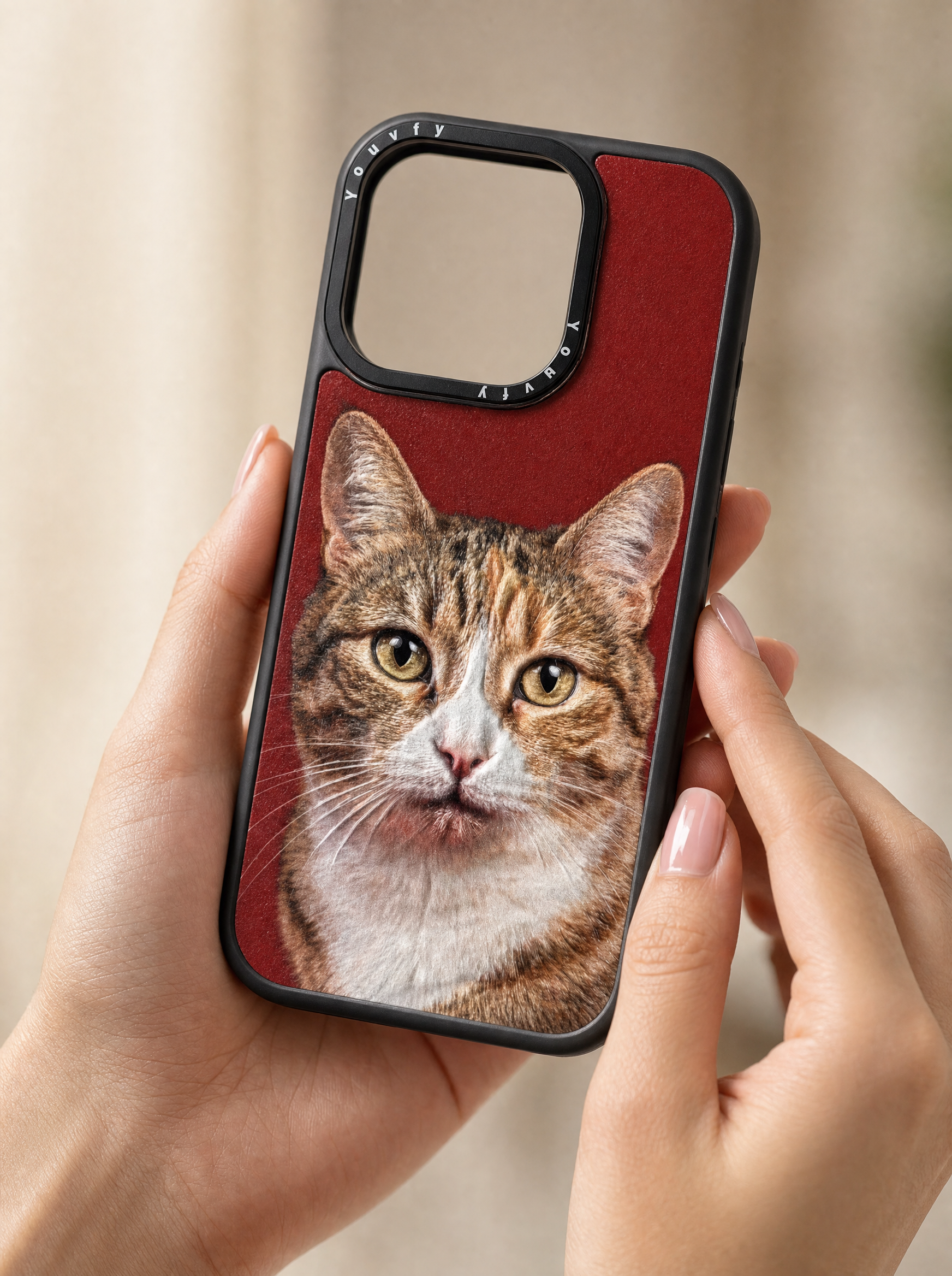 Elegant hands holding a Youvfy custom iPhone case with a tabby cat portrait on bold red