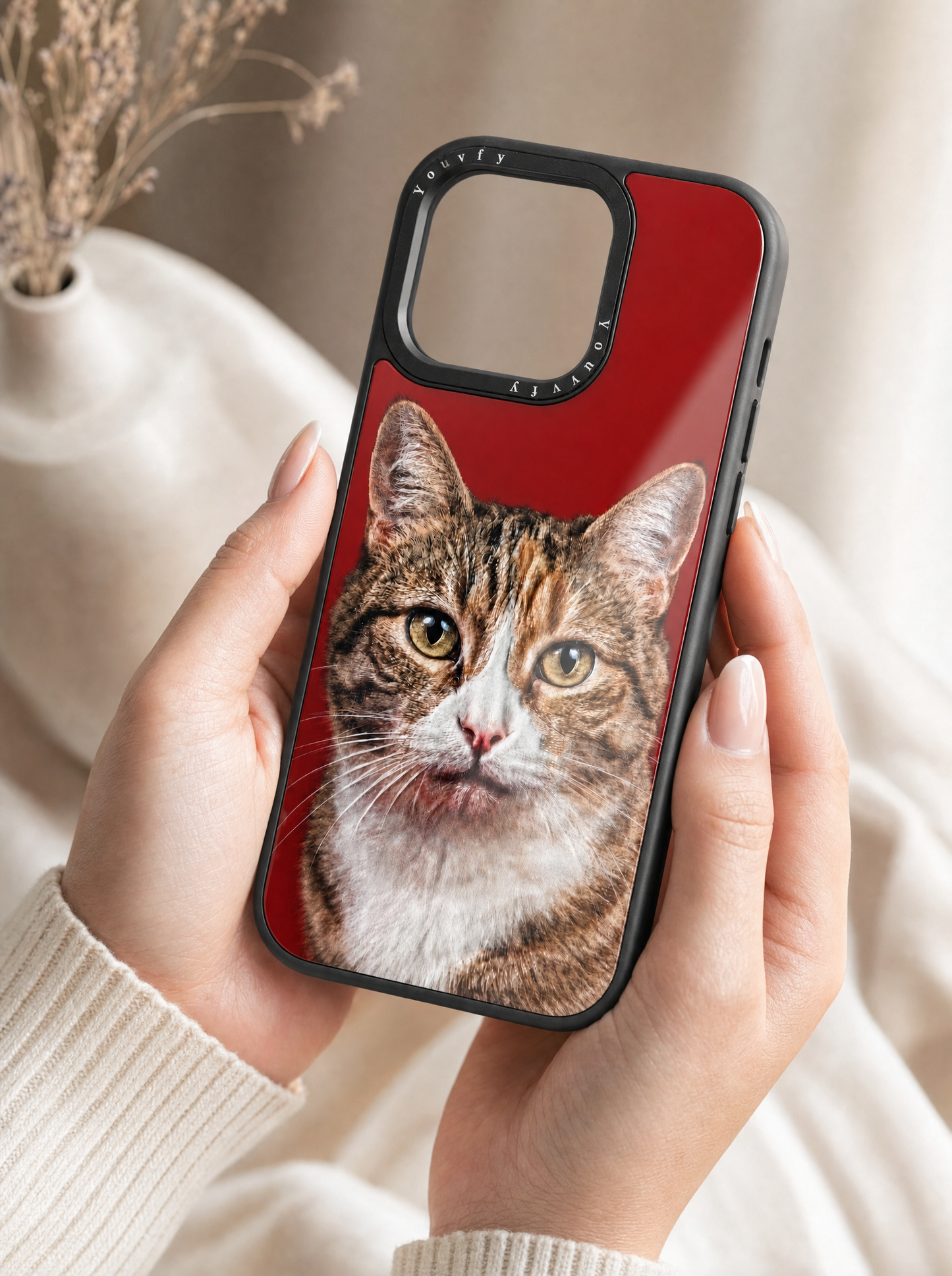 Elegant hands holding a Youvfy flat-printed iPhone case with a tabby cat portrait on bold red