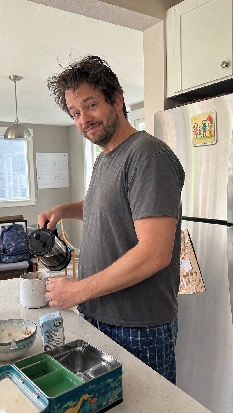 Customer photo: dad making coffee in his kitchen with his kid's crayon drawing turned into a Youvfy magnet on the fridge